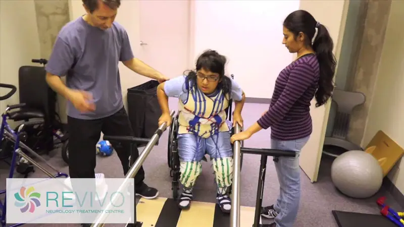 A teen working at the parallel bars in the TheraSuit with two Revivo therapists